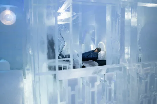Carved ice columns lining a cold hall lit from behind the walls